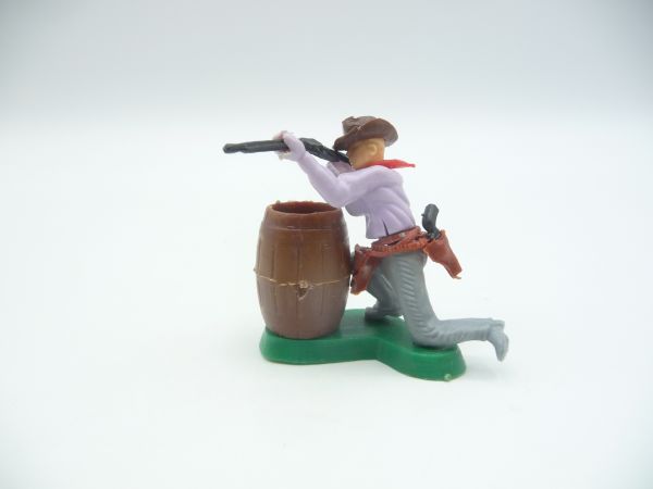 Cowboy kneeling behind barrel firing