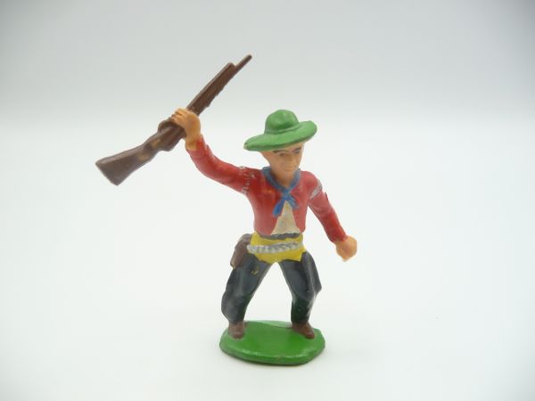 Cowboy standing, holding rifle high