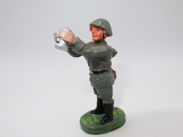 Soldier standing, holding gun shell upwards