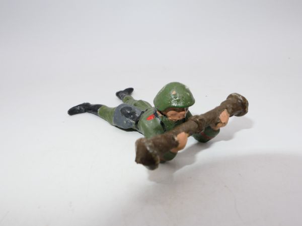 Soldat liegend mit schwerem Gerät vor dem Körper